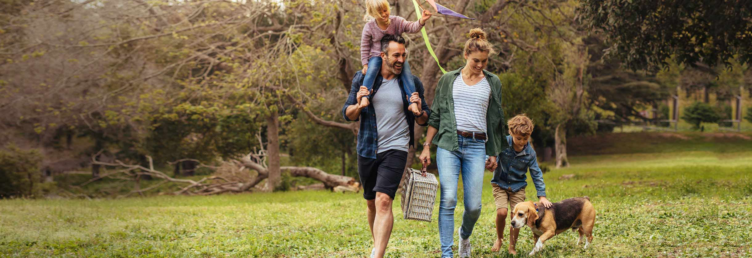 Family walking in a open field with their dog